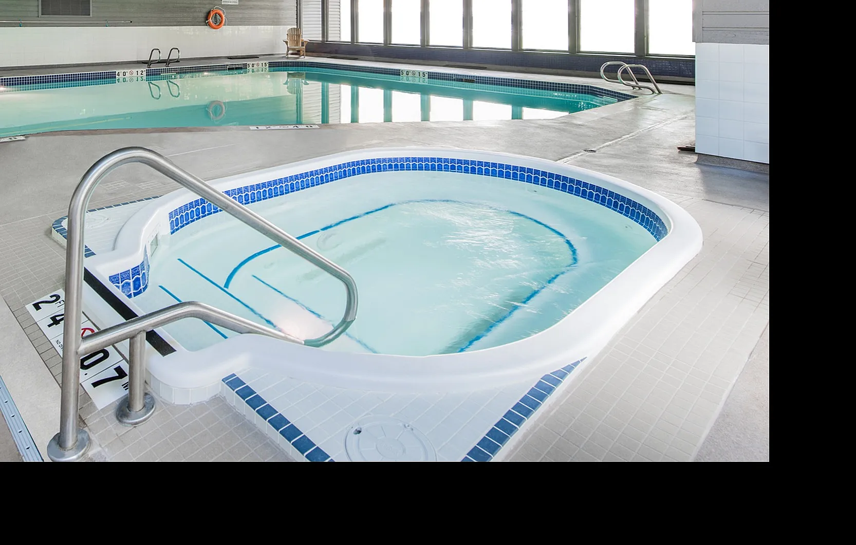 Inviting indoor pool and jacuzzi area with modern design and large windows providing natural light.