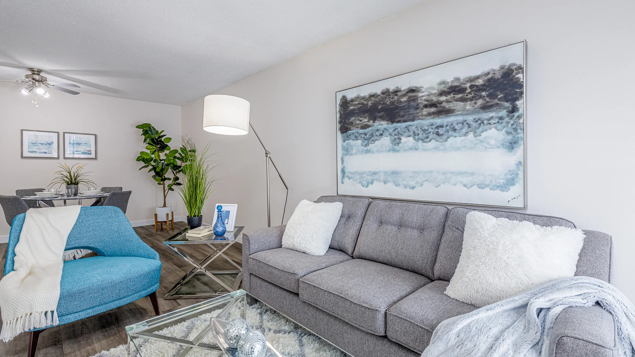 Contemporary living room with a plush grey sofa, stylish blue armchair, and modern decor.