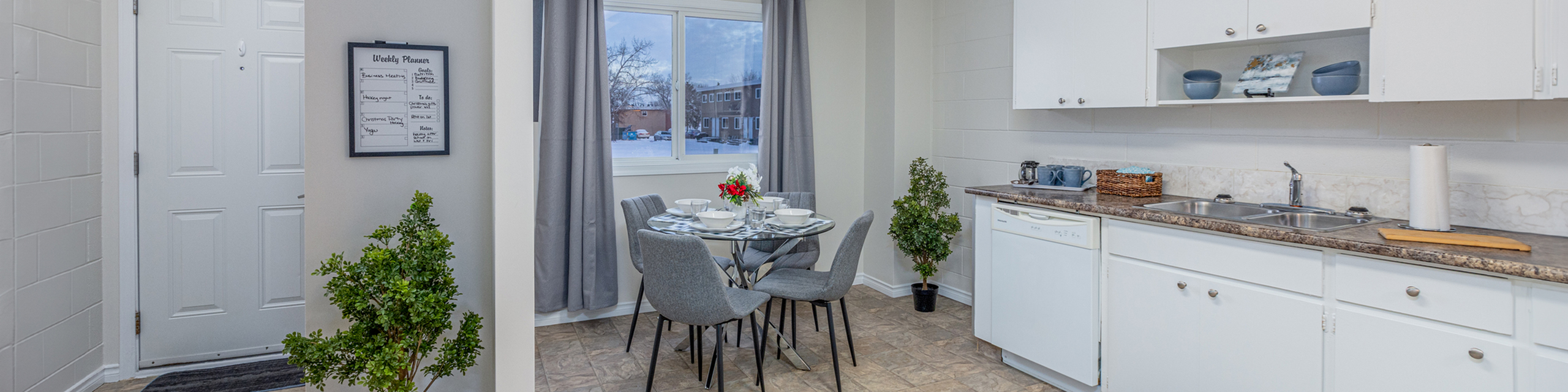 Bright and inviting kitchen with white cabinetry, a cozy dining nook set for four, and expansive windows letting in natural light.