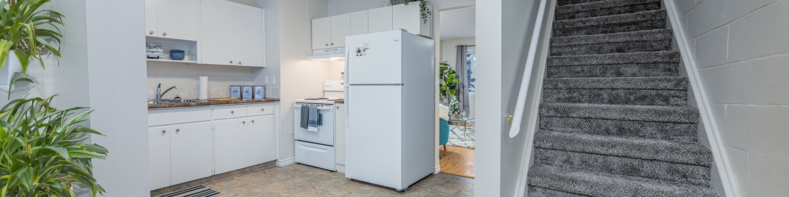 Bright and inviting kitchen with modern appliances, ample storage, and adjacent cozy carpeted staircase leading to the upper floor.