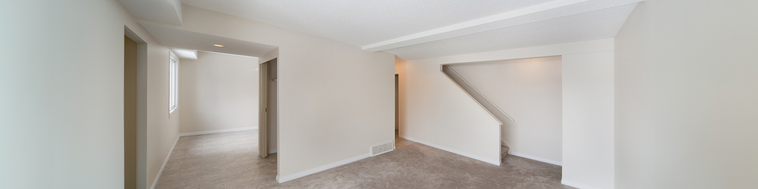 Bright and spacious room with modern neutral tones, featuring a cozy corner and ample natural light.