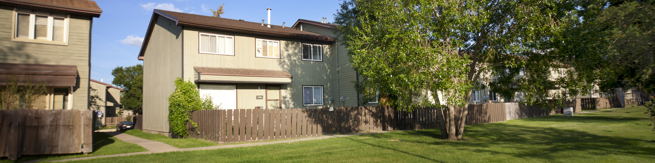 Charming townhouse property with lush green lawn and modern architecture, nestled in a peaceful suburban neighborhood.
