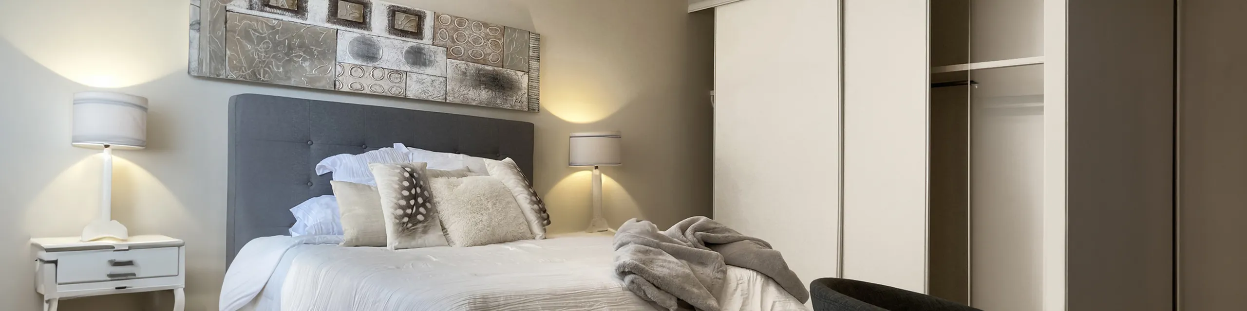 Elegant bedroom showcasing modern decor with a plush bed, stylish artwork, and ambient lighting.