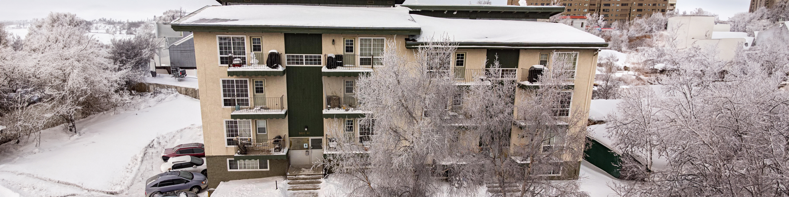 Charming apartment building enveloped in a picturesque snowy landscape, offering serene winter views.