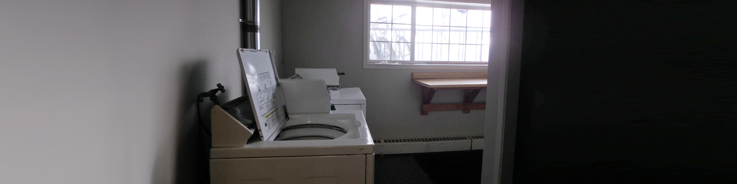 Bright laundry room with modern washing and drying machines and a large window for natural light.