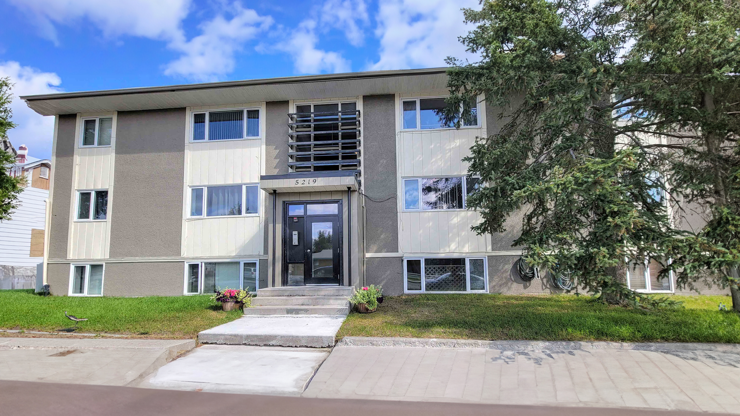 Charming apartment building with modern entrance and lush greenery, perfect for serene living.