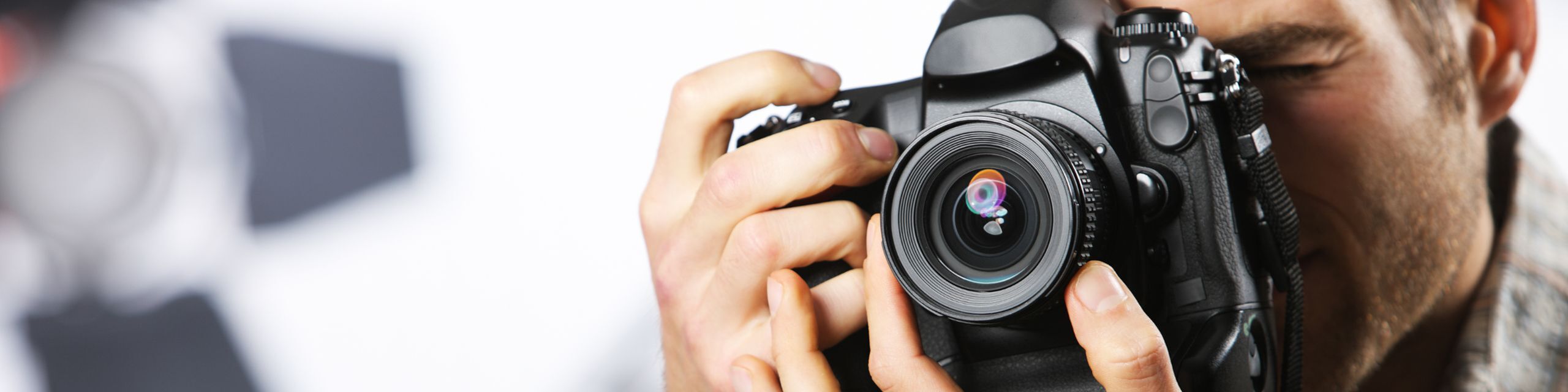 Close-up of a professional photographer holding a DSLR camera, capturing the perfect shot with precision and focus.