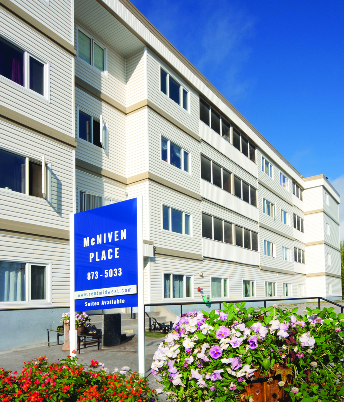 Bright and inviting apartment building with modern design and beautifully landscaped surroundings, featuring available suites at McNIVEN PLACE.