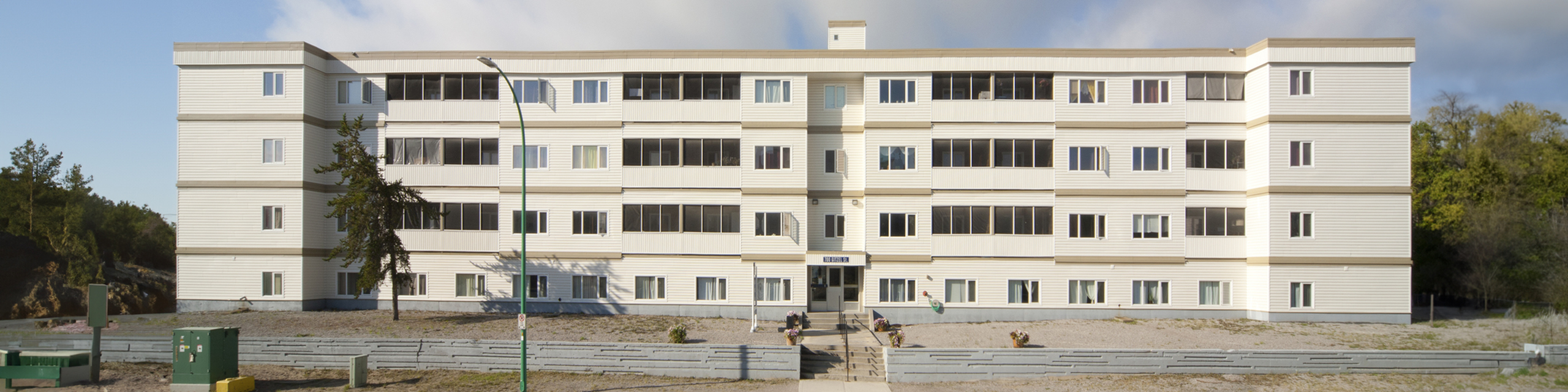 Charming four-story apartment building with a classic design, featuring large windows and surrounded by a tranquil natural landscape.