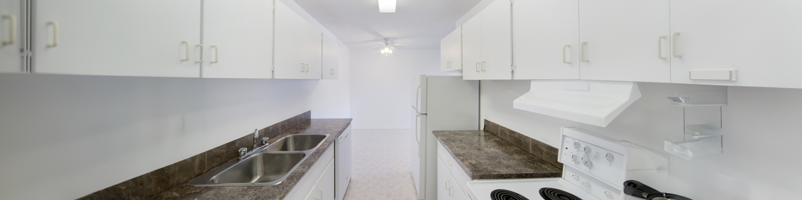 Bright, modern kitchen with sleek white cabinetry, dual sinks, and a spacious countertop, perfect for culinary creativity.