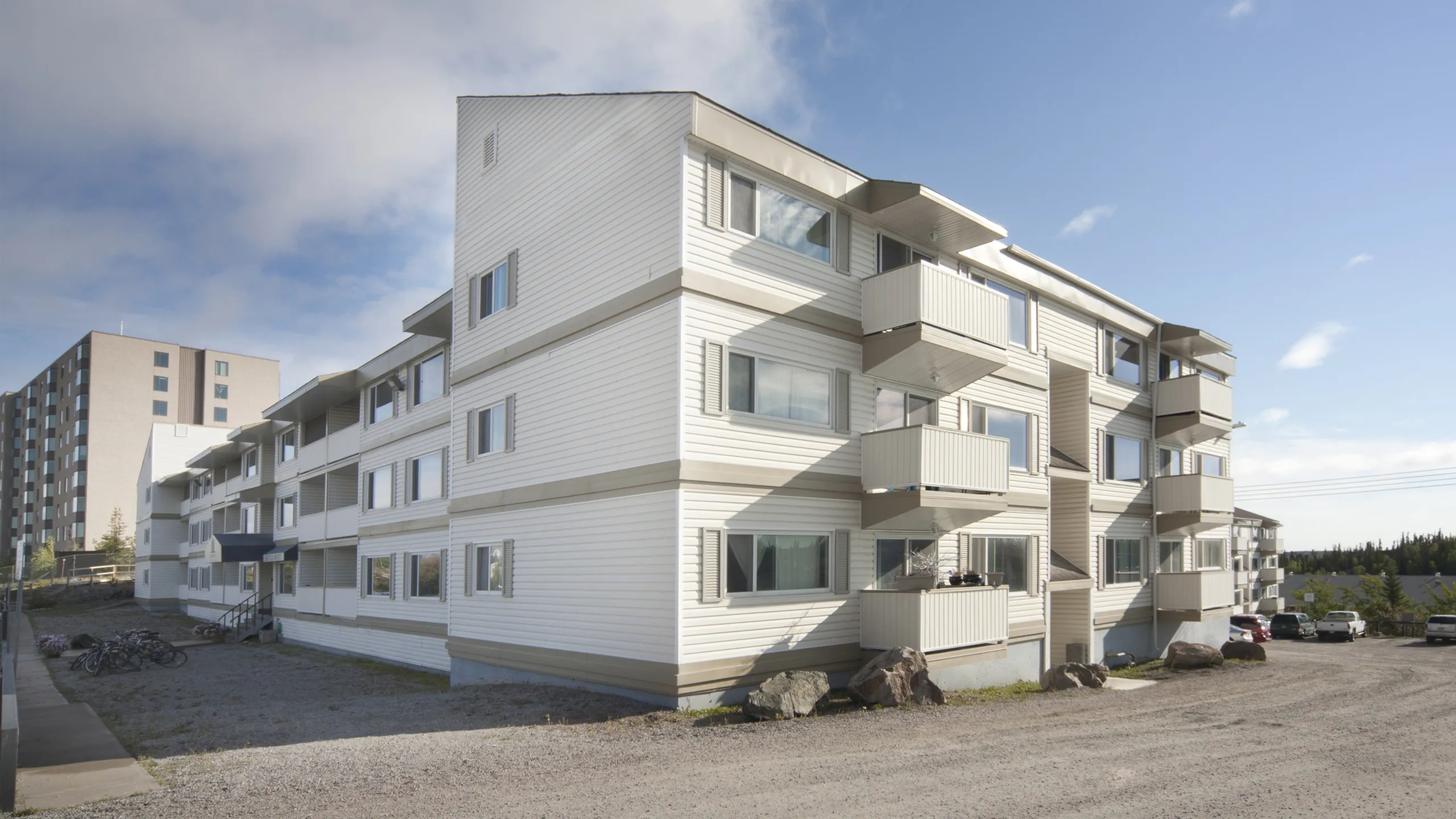 Charming multi-story apartment building with modern balconies and large windows, set against a bright sky, offering ample natural light.