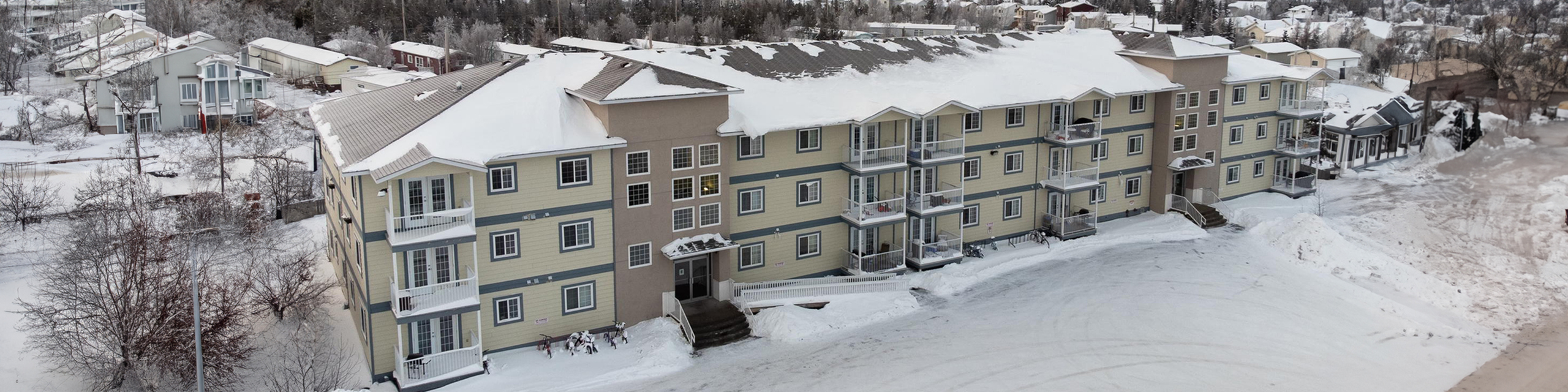 Charming snow-covered apartment building with spacious balconies offering serene winter views in a peaceful neighborhood.