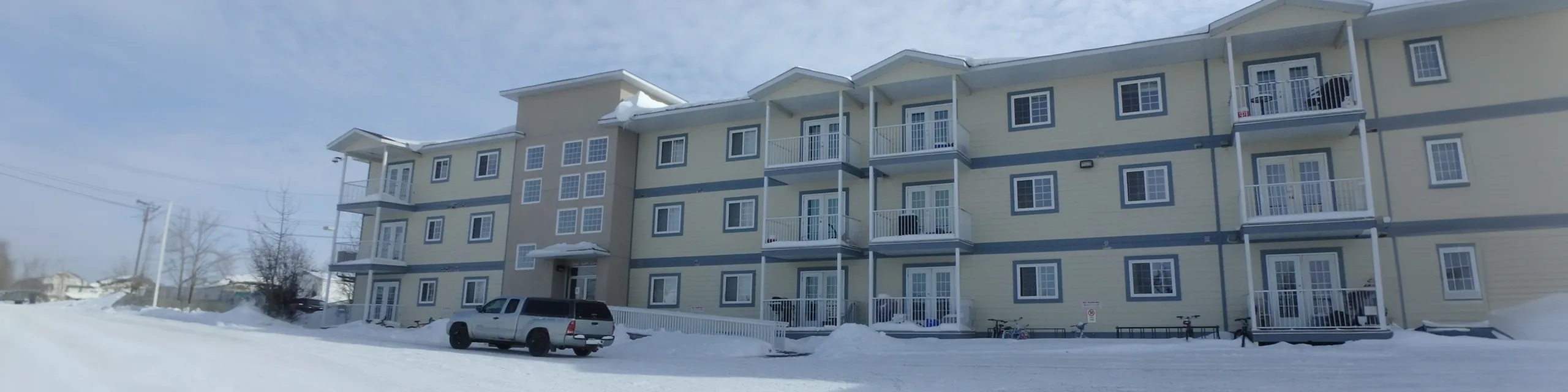 Charming apartment complex with modern balconies, nestled in a serene snowy setting.