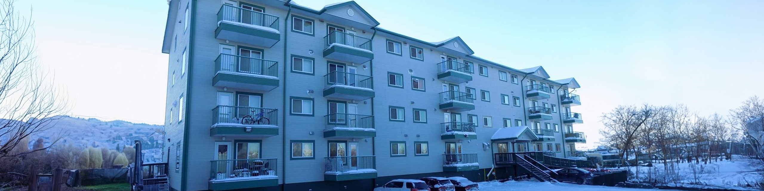 Charming apartment building with private balconies, nestled against scenic snowy mountains and serene surroundings.