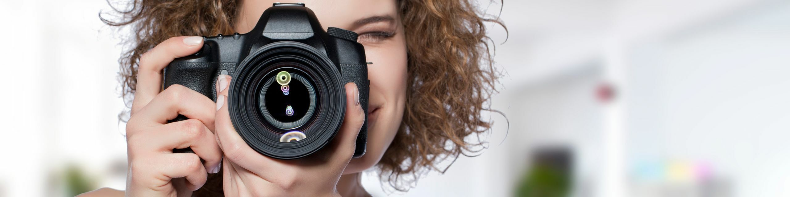 Close-up of a person holding a professional camera with a cheerful expression, capturing creative moments with clarity.