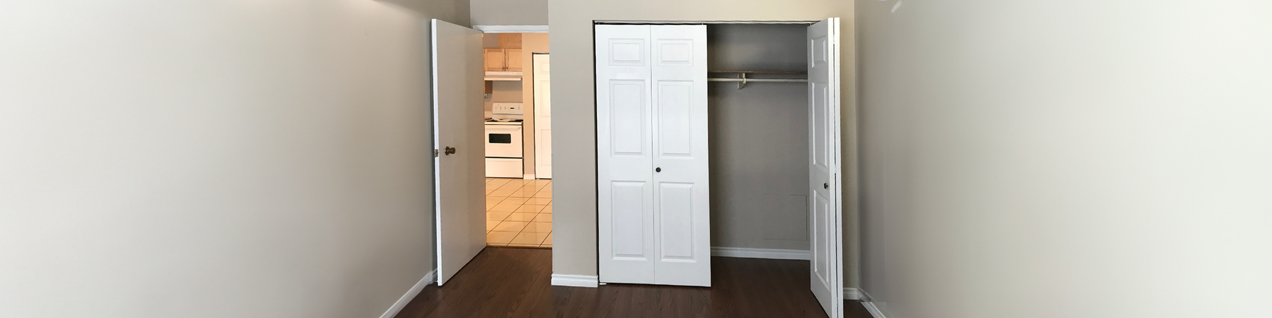 Inviting room showcasing sleek hardwood floors, ample closet space, and a warm kitchen glow.