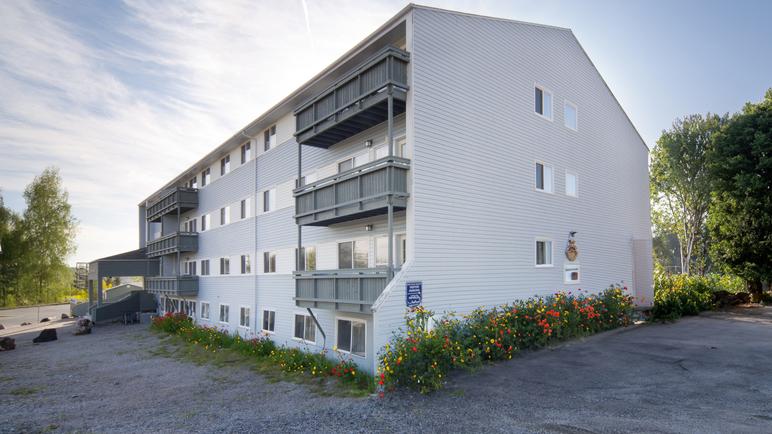 Charming multi-story apartment building with inviting balconies and vibrant garden landscape, perfect for modern living.