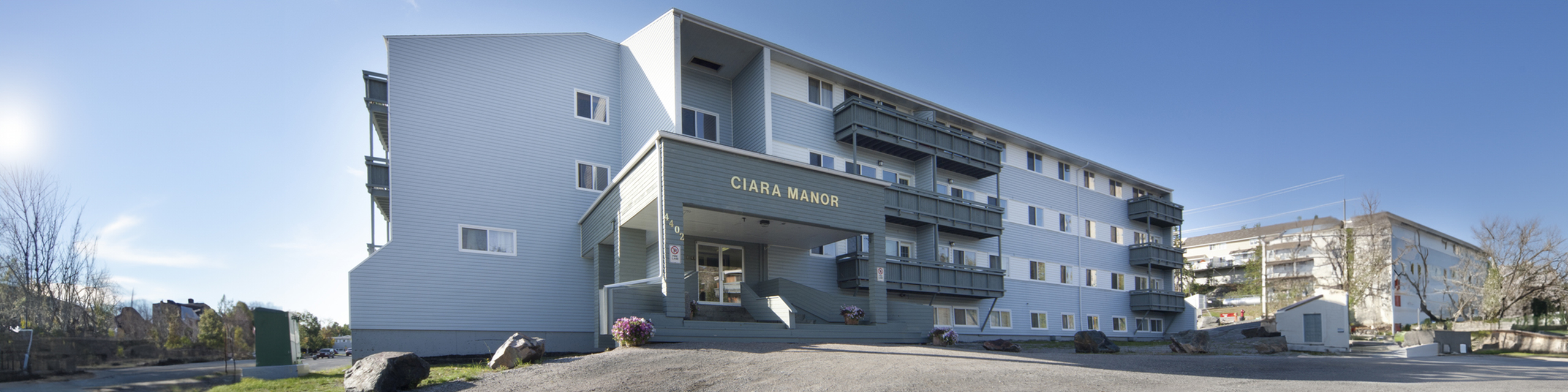 Elegant Ciara Manor apartment building with modern exterior and private balconies set against a clear blue sky.