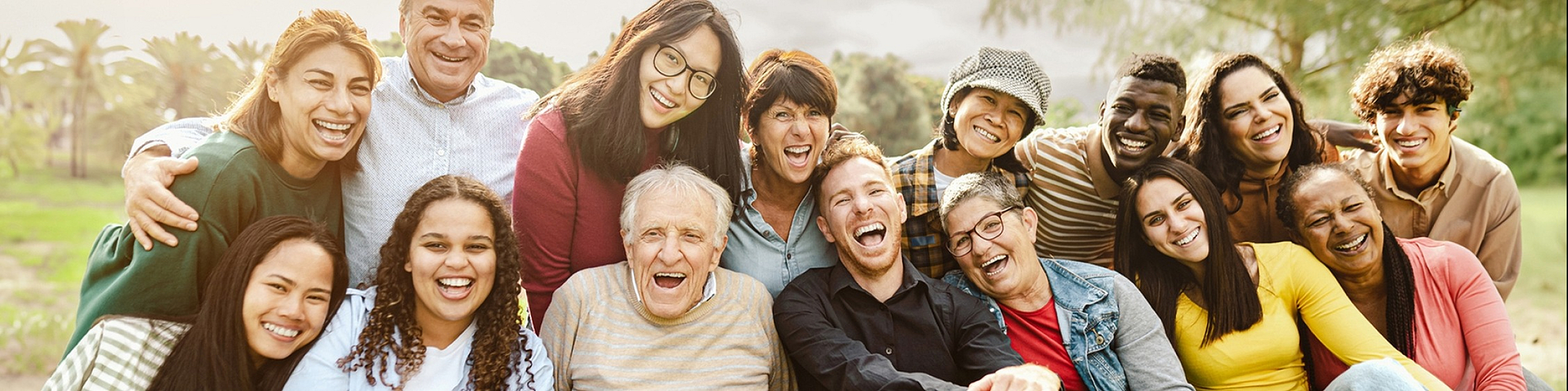 Joyful group of diverse people smiling in an outdoor setting, showcasing community and togetherness.