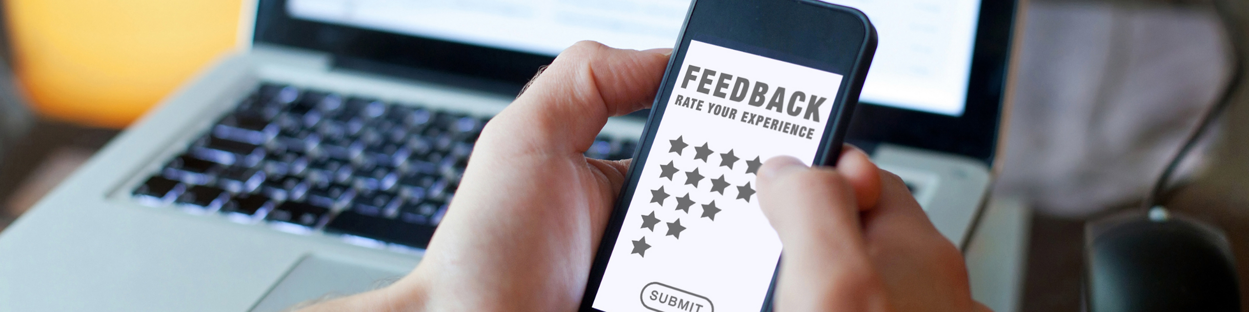 Close-up of a person providing feedback using a smartphone, featuring a star rating system, conveying a modern digital experience.