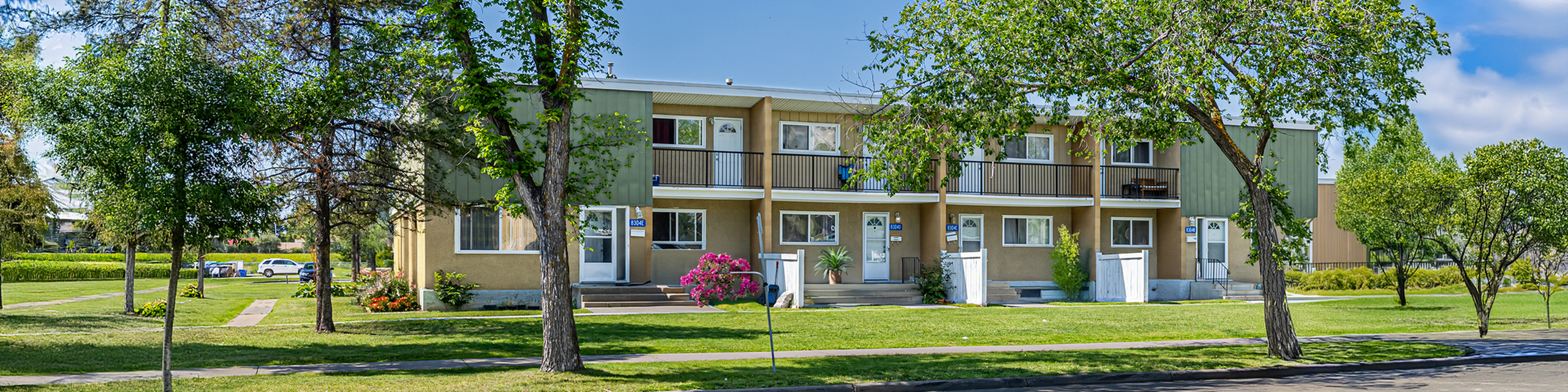 Charming townhouse complex with lush green lawns and vibrant trees, creating a serene neighborhood atmosphere.