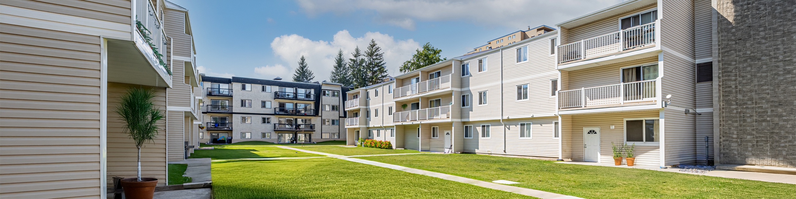 Inviting apartment exterior with modern balconies, well-maintained lawns, and a bright, sunny atmosphere.