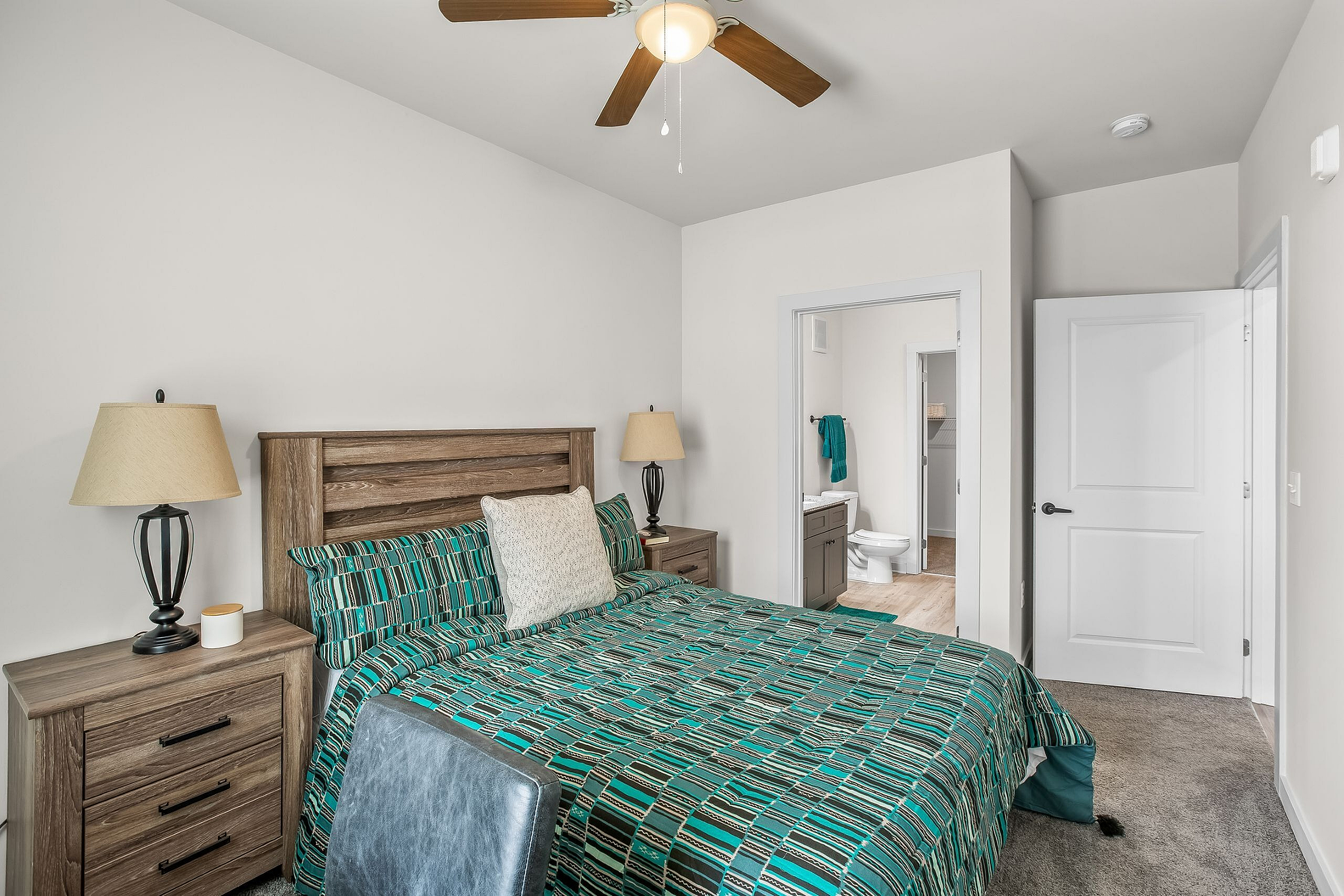 Inviting bedroom with stylish wooden furniture, vibrant bedding, and an ensuite bathroom, perfect for cozy relaxation.