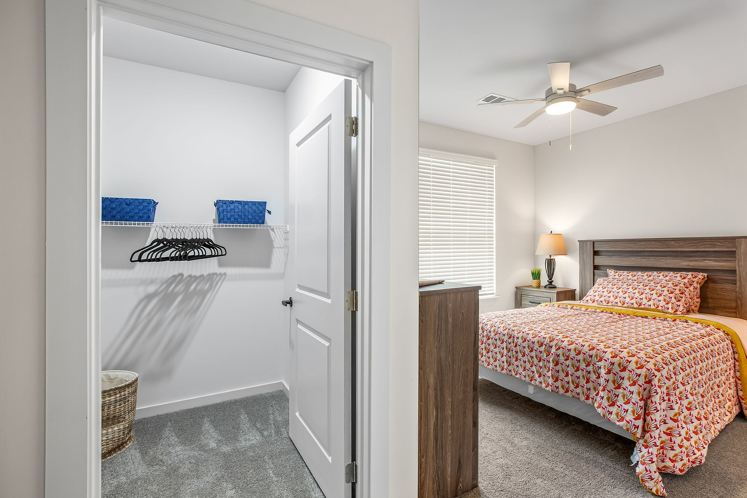 Charming bedroom with cozy patterned bedding, warm lamp lighting, ceiling fan, and a spacious walk-in closet for convenient storage.