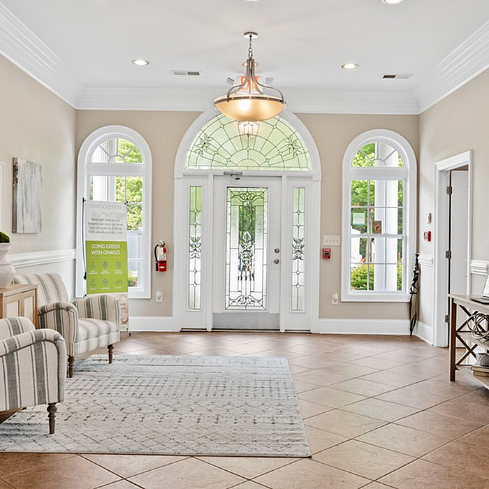 Bright and welcoming entrance with arched windows, stylish chandelier, and comfortable seating.
