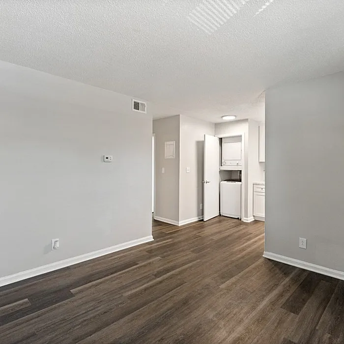 Bright modern apartment featuring sleek hardwood floors and a compact in-unit laundry space.