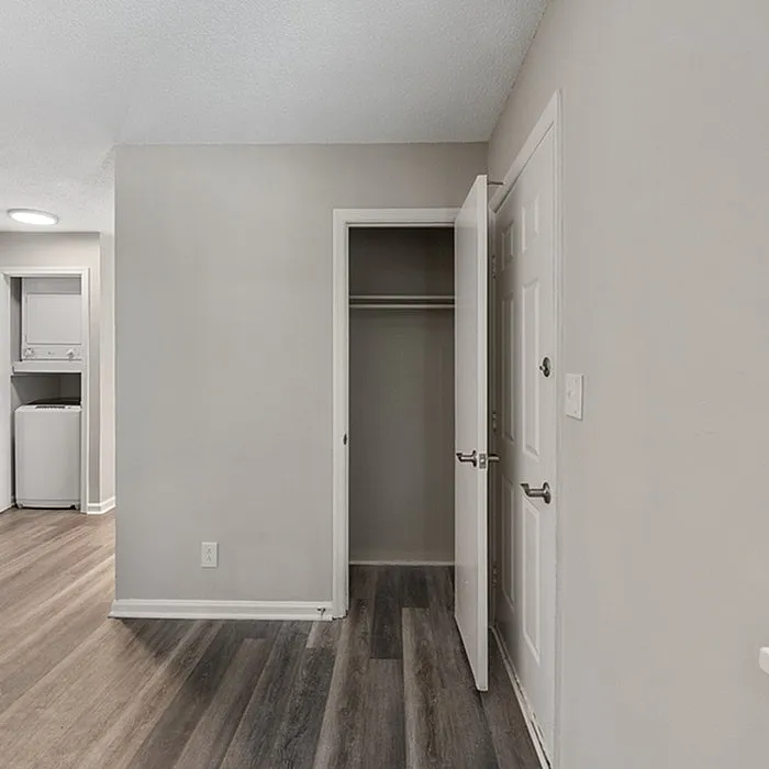 Inviting apartment corner with closet, modern appliances, and stylish wood flooring.