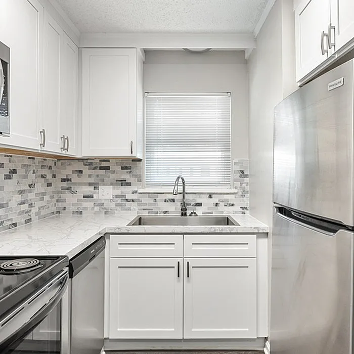 Bright and modern kitchen with stainless steel appliances, white cabinets, and marble countertops.