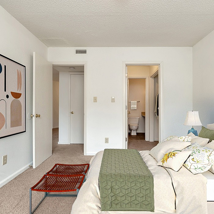 Inviting bedroom featuring a plush bed, modern art, and convenient access to an ensuite bathroom.