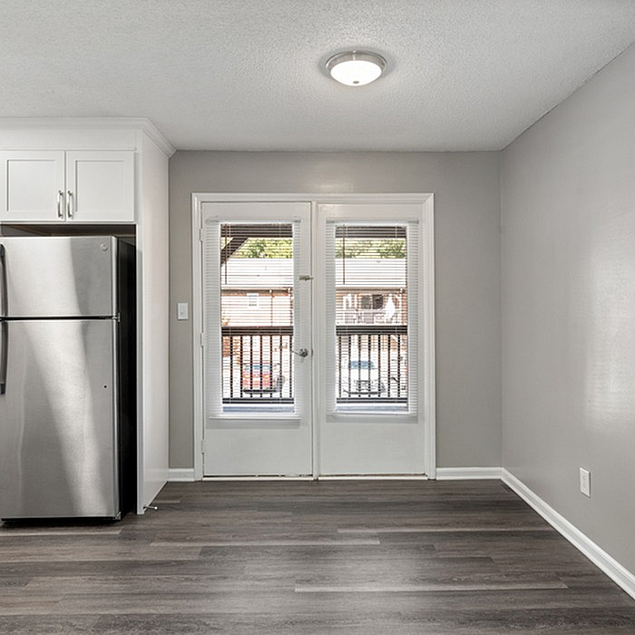 Bright kitchen area with modern stainless steel refrigerator and French doors leading to a balcony view.