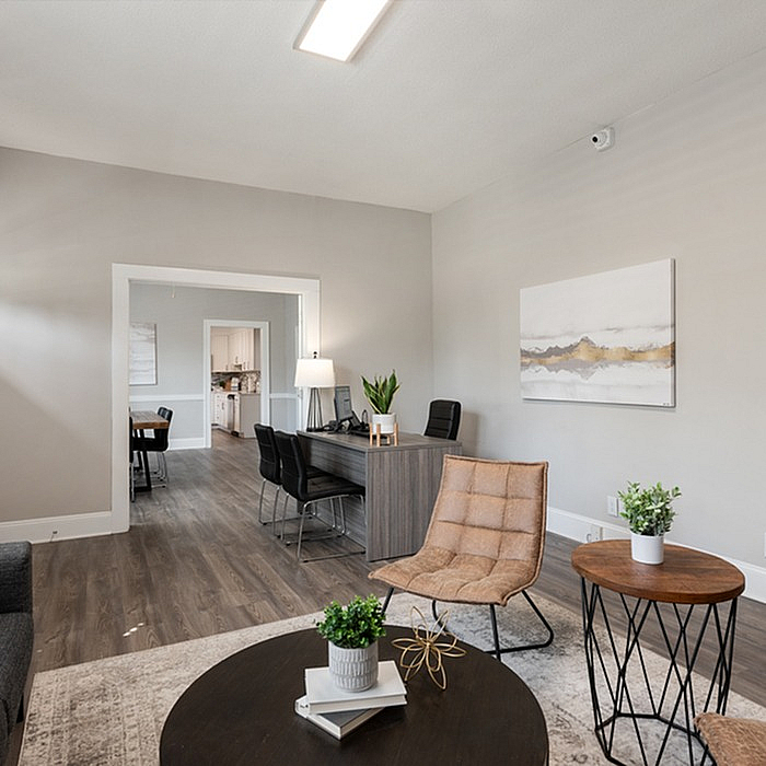 Modern living room with elegant furnishings, including a cozy chair, stylish wooden tables, and sleek workspace.