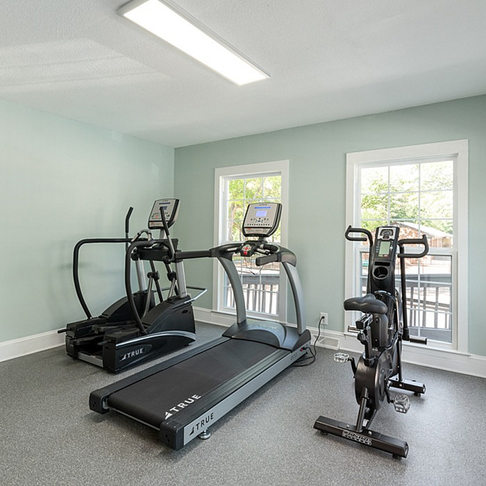 Modern home gym with treadmill, elliptical, and stationary bike in a well-lit space.