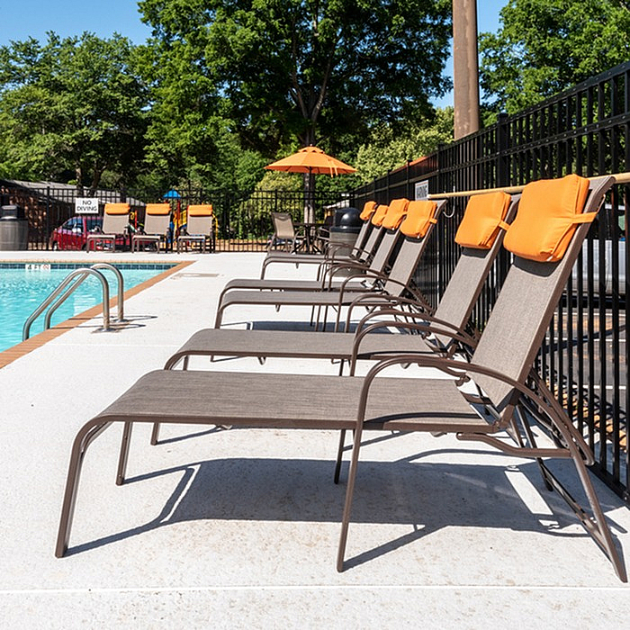 Inviting outdoor pool area with sun loungers and vibrant orange accents, perfect for relaxation.