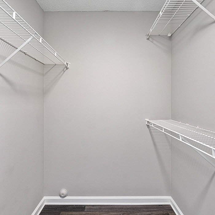 Spacious walk-in closet with sleek white shelving, perfect for ample storage and organization.