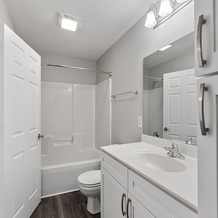Bright and modern bathroom with sleek white cabinetry, chic lighting, and a spacious bathtub.