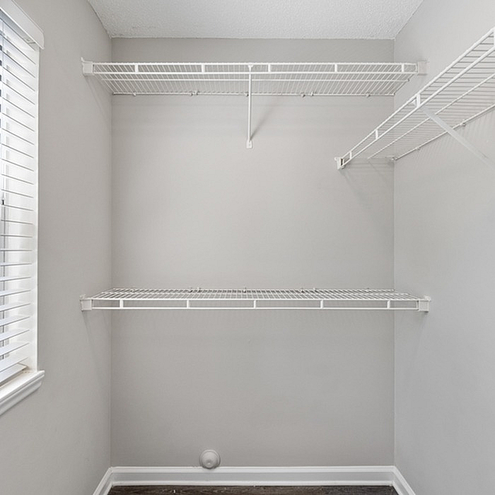 Bright and spacious walk-in closet with sleek white wire shelving, perfect for organized living.