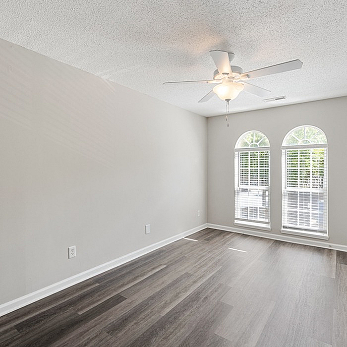 Bright, empty room boasting elegant wooden flooring and arched windows, ideal for a cozy living space.
