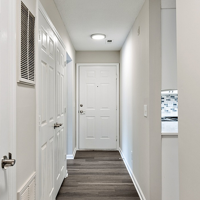 Inviting apartment entryway with sleek hardwood floors, freshly painted walls, and elegant white doors leading to modern interiors.