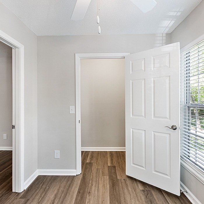 Inviting apartment interior showcasing a modern, open doorway with elegant wooden flooring, abundant natural light through large windows, and a clean, neutral color palette.