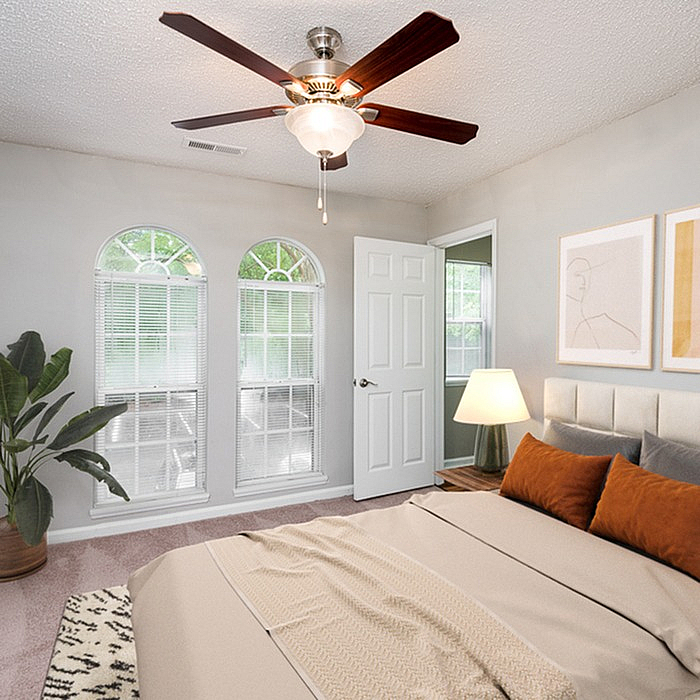 Bright and inviting bedroom with elegant ceiling fan, stylish arched windows, and tasteful decor.