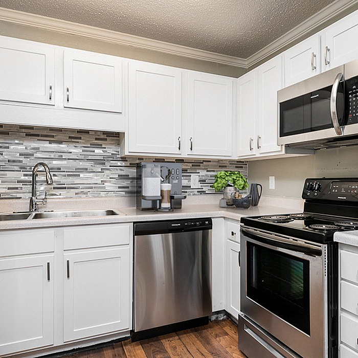 Modern kitchen with sleek stainless steel appliances, white cabinetry, and a stylish tiled backsplash.