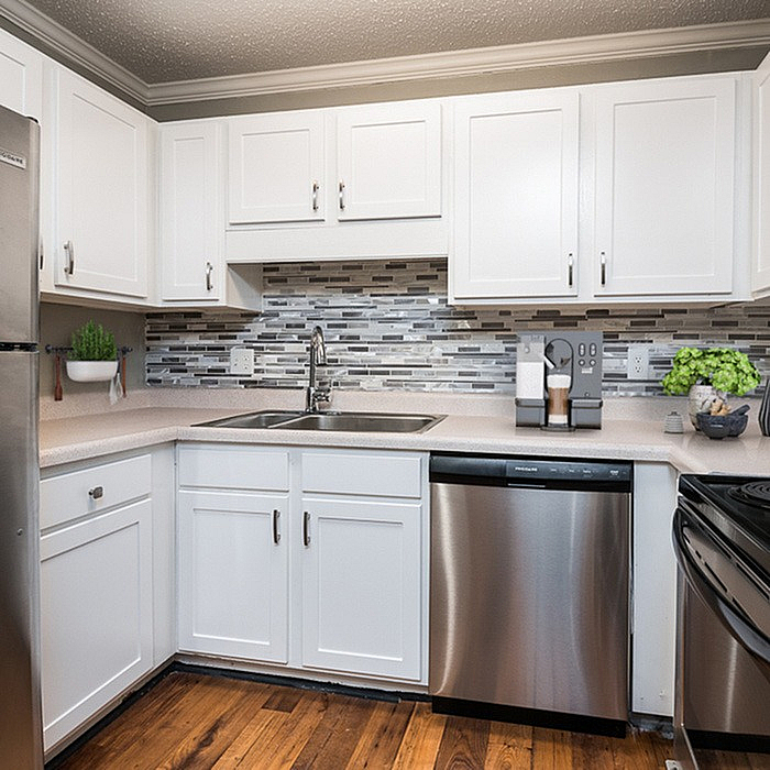 Modern kitchen with sleek stainless steel appliances, elegant white cabinetry, and a stylish mosaic tile backsplash.
