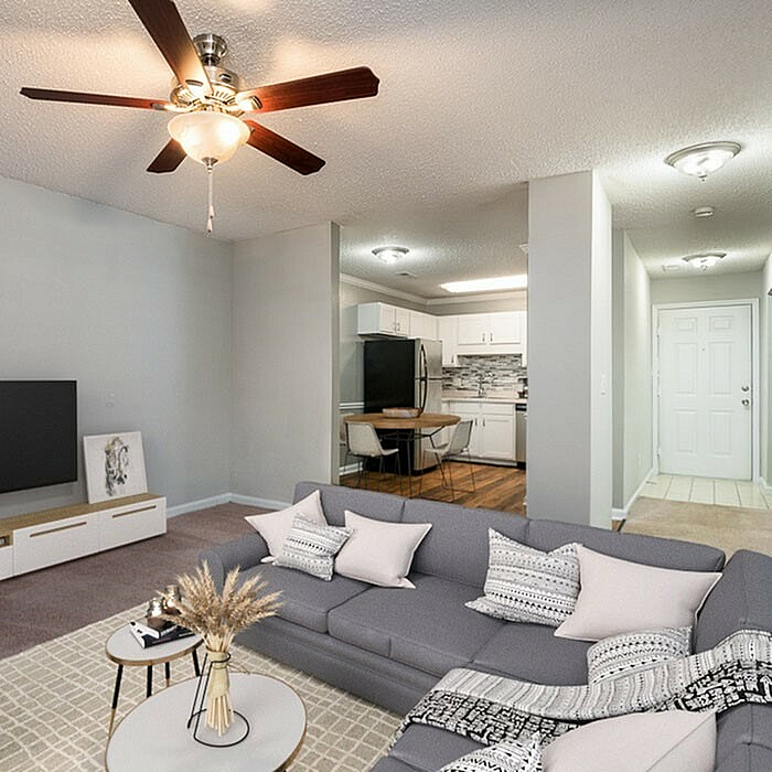 Cozy open-concept living room with stylish sectional sofa, modern ceiling fan, and a sleek adjacent kitchen with chic cabinetry.