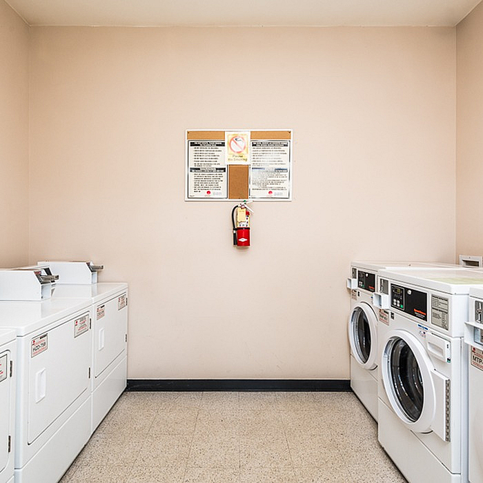 Modern laundry room with multiple washers and dryers, featuring a bright and clean design for convenient living.