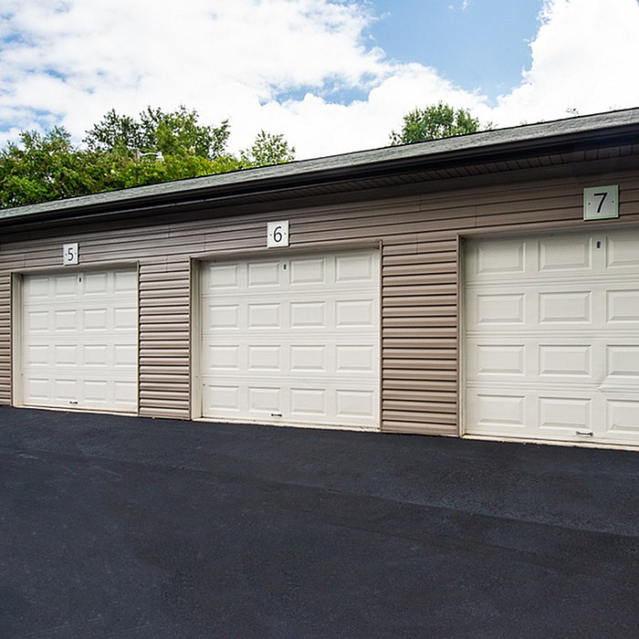 Modern and secure garage units with sleek white doors, providing ample storage space in a landscaped community setting.