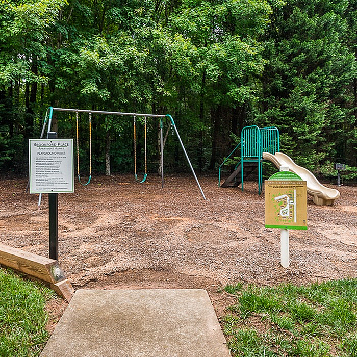 Inviting playground with swings and slides surrounded by lush green trees, perfect for family fun and outdoor activities.